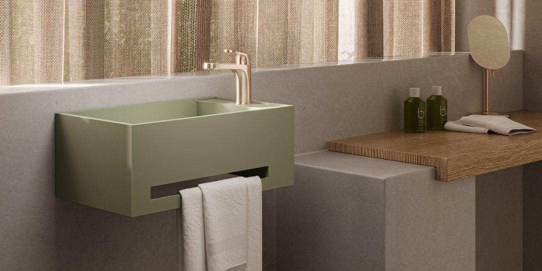Lavabo suspendido color verde oliva con toallero integrado y grifería dorada en baño moderno con decoración minimalista.