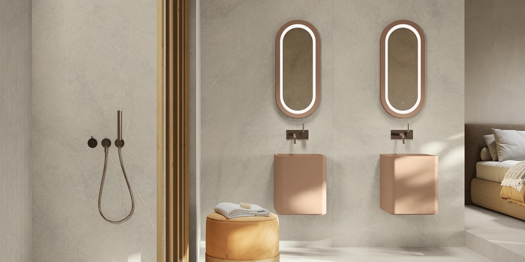 Baño minimalista con doble lavabo suspendido en tonos tierra y espejos ovalados retroiluminados.