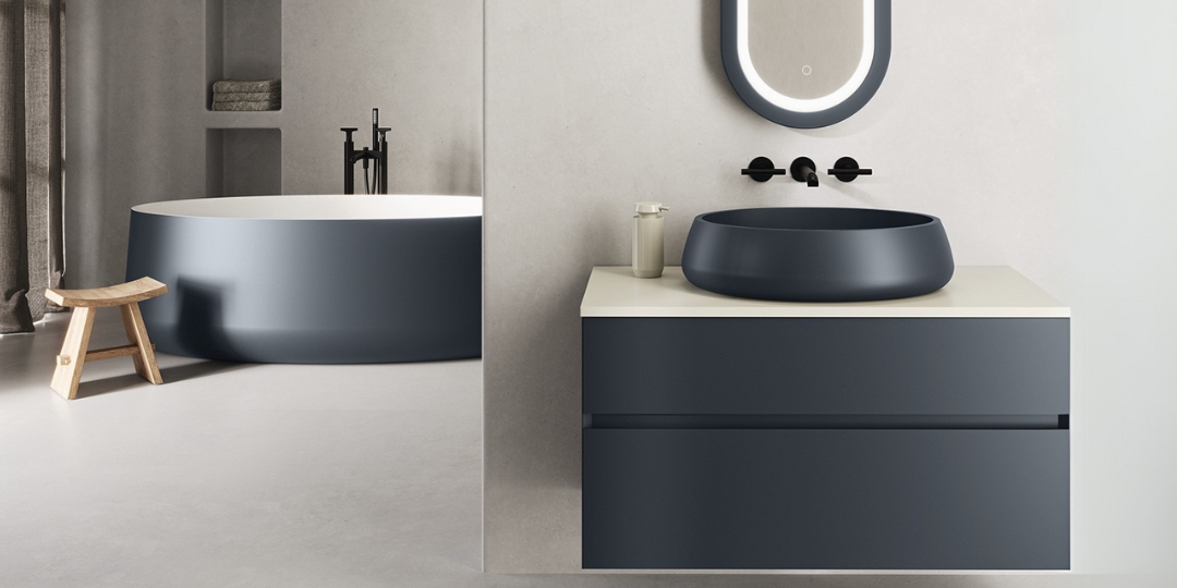 Baño de diseño con lavabo sobre encimera y bañera azul mate, muebles minimalistas y espejo retroiluminado.